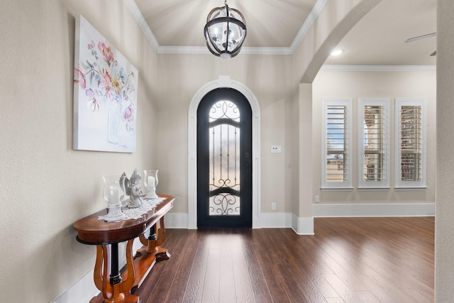 foyer entrance featuring dark wood-style floors, baseboards, arched walkways, and ornamental molding