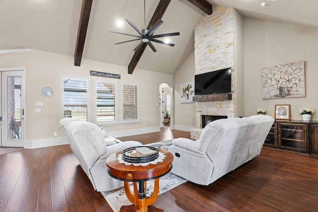 living room with arched walkways, a fireplace, baseboards, beam ceiling, and dark wood-style floors