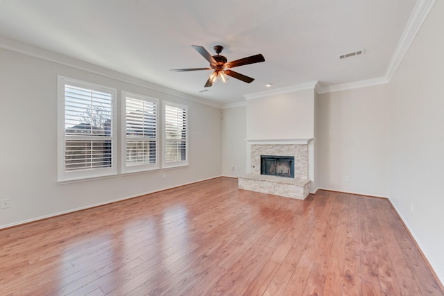 unfurnished living room featuring crown molding, a stone fireplace, and light hardwood / wood-style flooring