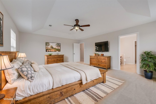 carpeted bedroom with ceiling fan and a raised ceiling