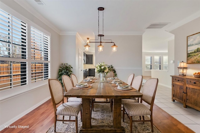 dining room with crown molding and light hardwood / wood-style floors