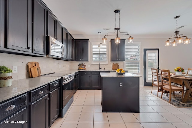 kitchen with light stone counters, decorative light fixtures, stainless steel appliances, and a center island