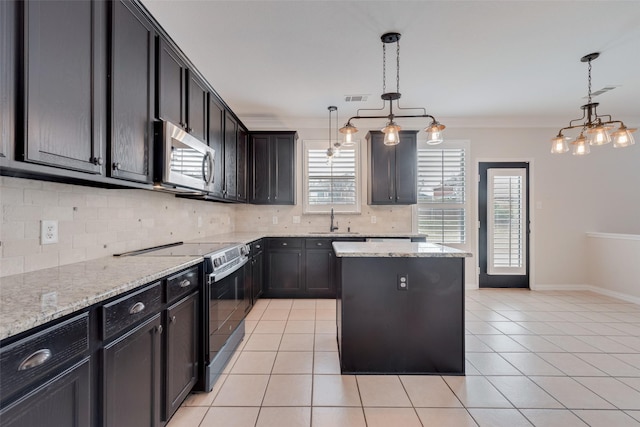 kitchen with appliances with stainless steel finishes, a center island, light stone counters, and decorative light fixtures