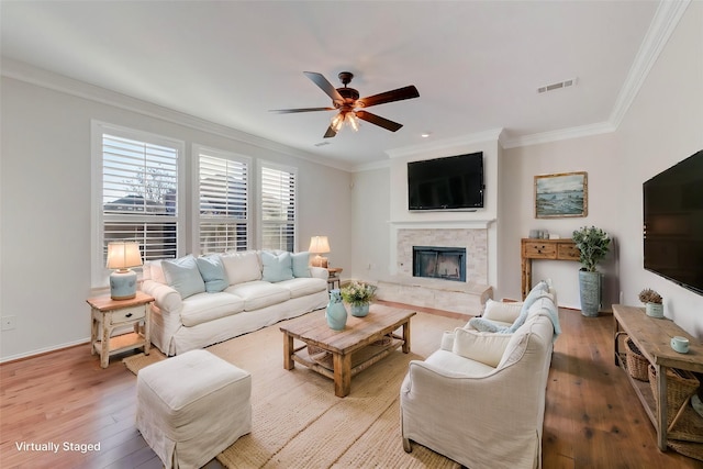 living room featuring a fireplace, crown molding, and wood-type flooring