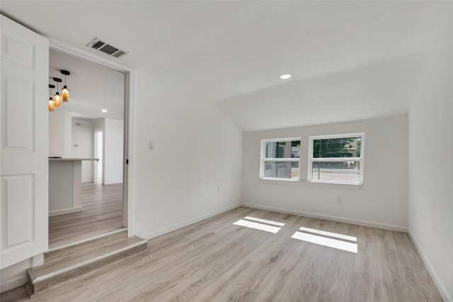 unfurnished room with lofted ceiling and light wood-type flooring