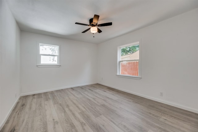 empty room with ceiling fan, plenty of natural light, and light wood-type flooring