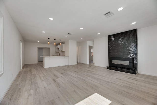 unfurnished living room with a large fireplace and light hardwood / wood-style floors