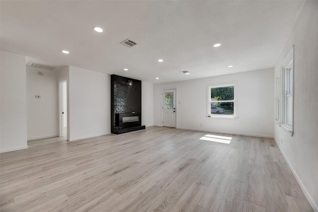 unfurnished living room featuring a multi sided fireplace and light hardwood / wood-style flooring