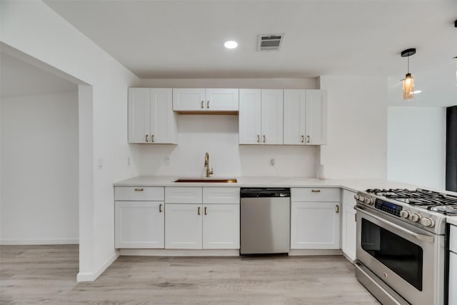 kitchen featuring appliances with stainless steel finishes, sink, hanging light fixtures, and white cabinets