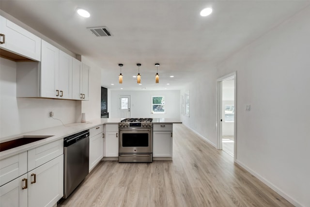 kitchen with appliances with stainless steel finishes, pendant lighting, white cabinets, kitchen peninsula, and light wood-type flooring