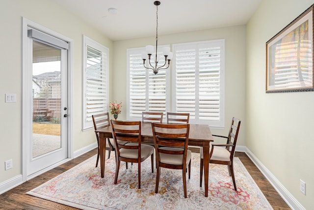 dining space featuring dark wood-type flooring, a wealth of natural light, and a notable chandelier