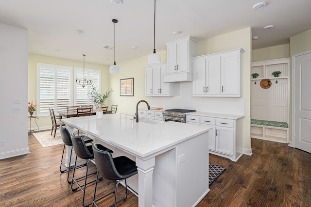 kitchen featuring white cabinetry, sink, decorative light fixtures, and a center island with sink