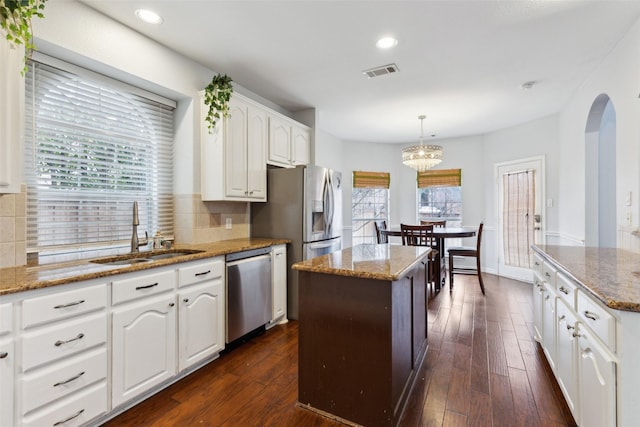 kitchen with pendant lighting, white cabinetry, sink, a center island, and stainless steel appliances