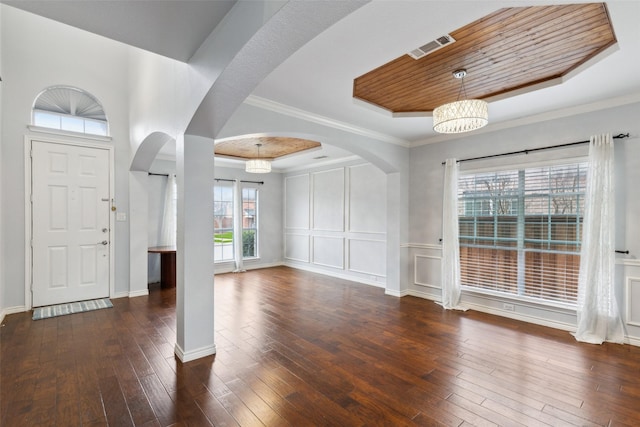 foyer with dark hardwood / wood-style floors, a tray ceiling, ornamental molding, wooden ceiling, and a chandelier