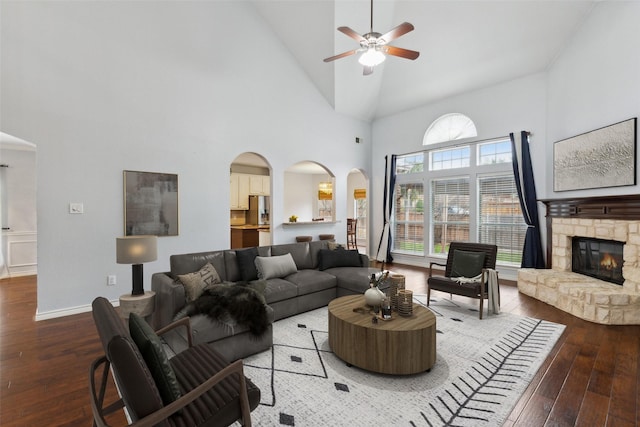 living room with ceiling fan, high vaulted ceiling, a fireplace, and hardwood / wood-style floors