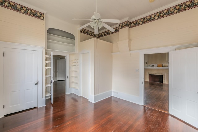 spare room with crown molding, ceiling fan, dark hardwood / wood-style flooring, and built in features