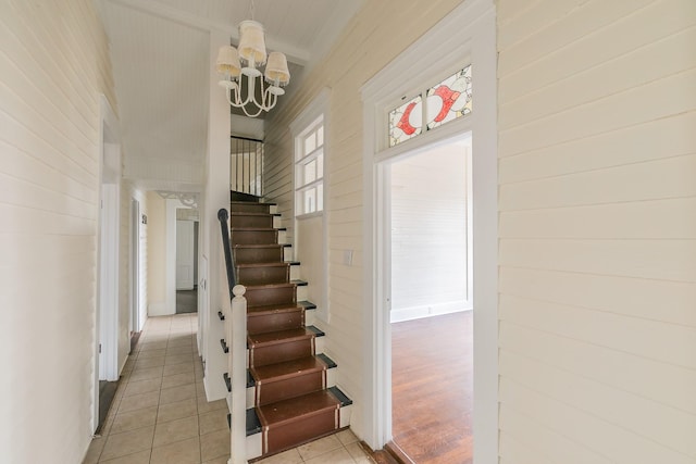 stairway featuring a notable chandelier, tile patterned floors, and wood walls