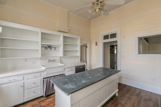 kitchen with sink, a center island, ornamental molding, white cabinets, and dark hardwood / wood-style flooring