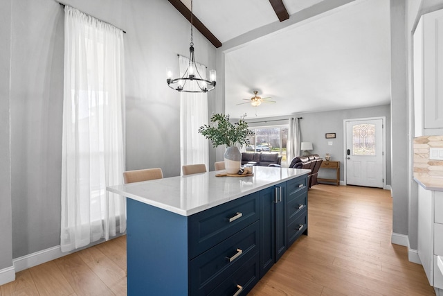 kitchen with decorative light fixtures, blue cabinets, vaulted ceiling with beams, a center island, and light wood-type flooring