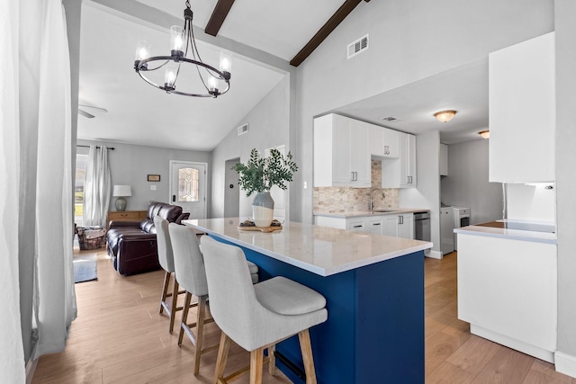 kitchen with pendant lighting, separate washer and dryer, white cabinets, a kitchen breakfast bar, and light wood-type flooring