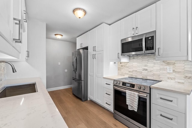 kitchen featuring light stone counters, sink, white cabinets, and appliances with stainless steel finishes