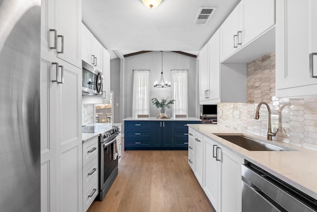 kitchen featuring white cabinetry, hanging light fixtures, blue cabinetry, and appliances with stainless steel finishes