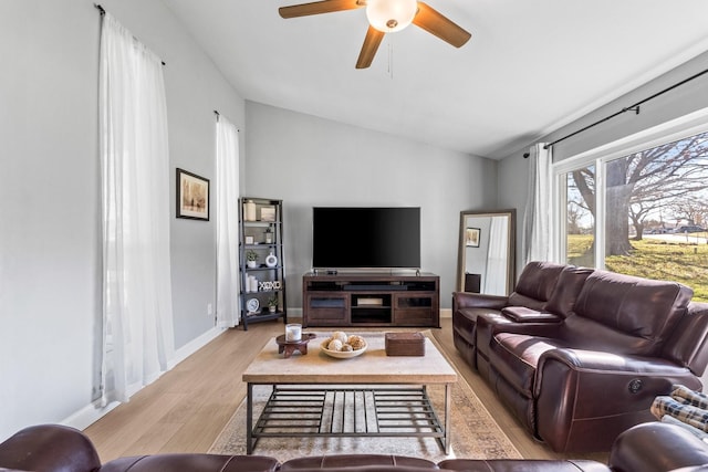 living room with ceiling fan, vaulted ceiling, and light wood-type flooring