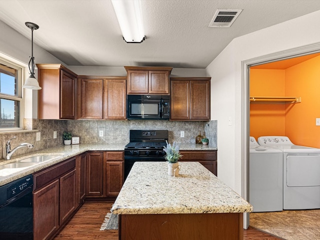 kitchen with pendant lighting, sink, black appliances, a kitchen island, and separate washer and dryer