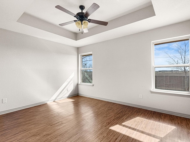 unfurnished room with ceiling fan, a tray ceiling, and hardwood / wood-style floors