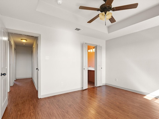 unfurnished room with a raised ceiling, wood-type flooring, and ceiling fan