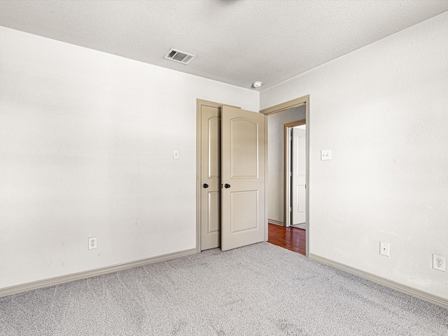 carpeted spare room with a textured ceiling