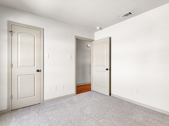 unfurnished bedroom featuring light carpet and a textured ceiling