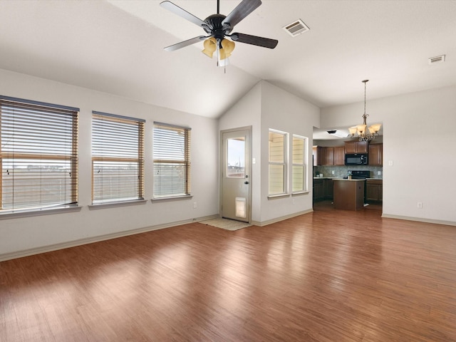 unfurnished living room with ceiling fan with notable chandelier, dark hardwood / wood-style flooring, and vaulted ceiling