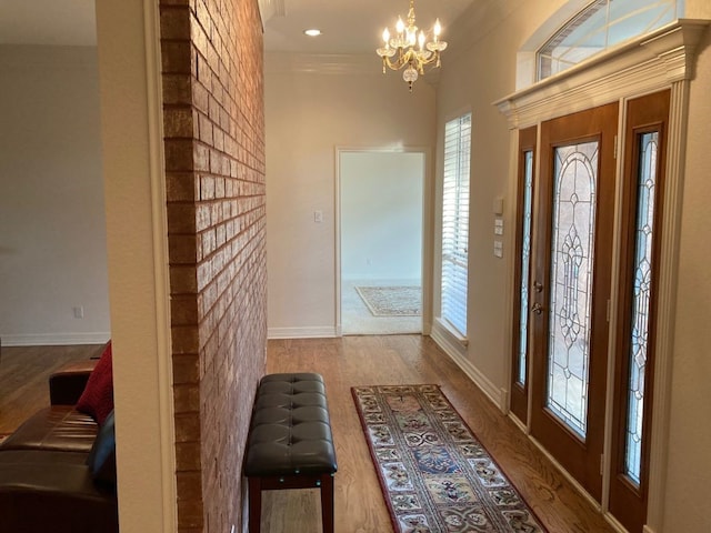 entrance foyer featuring an inviting chandelier, crown molding, and wood-type flooring