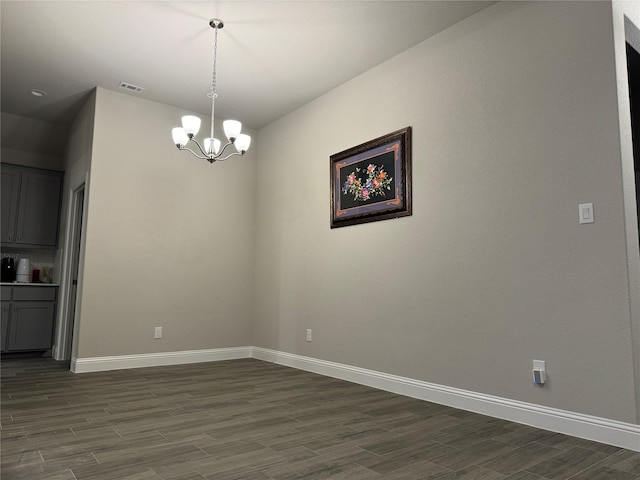 unfurnished dining area featuring dark hardwood / wood-style flooring and a chandelier