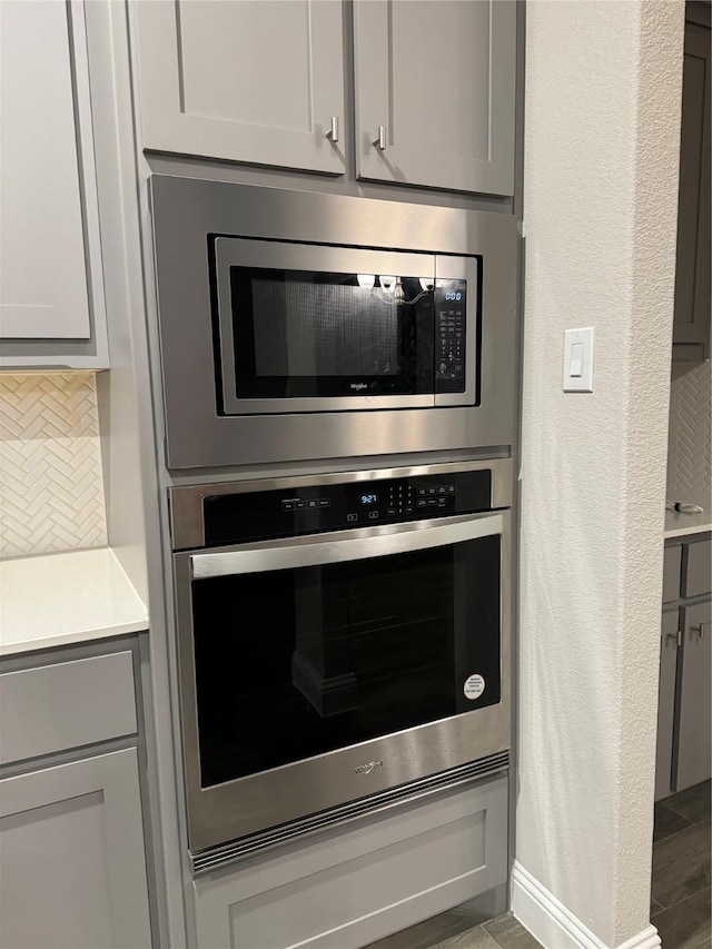 room details featuring stainless steel appliances, gray cabinets, and backsplash