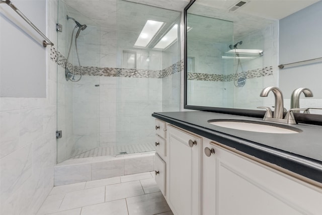 bathroom with a shower with door, vanity, tile walls, and tile patterned floors