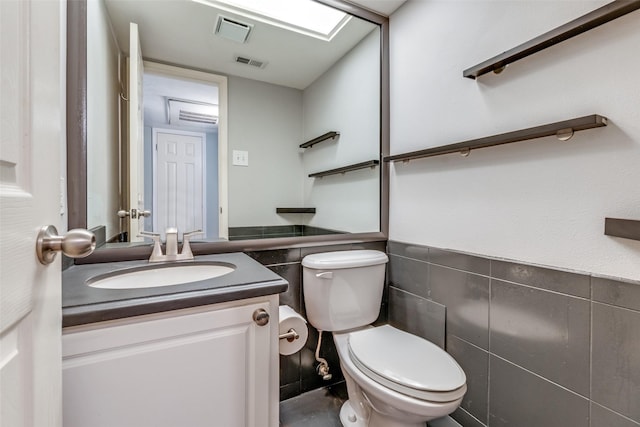 bathroom with vanity, toilet, and tile walls