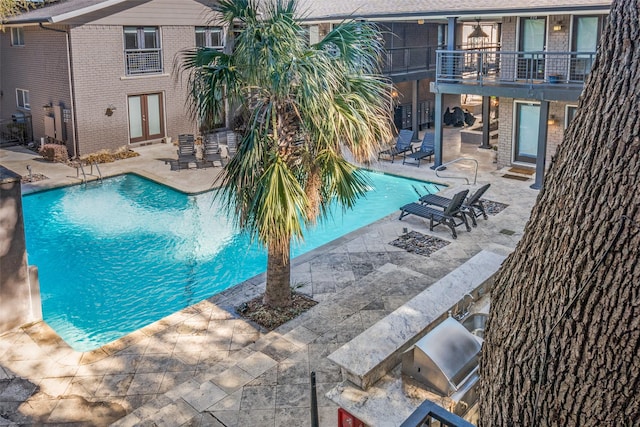 view of pool featuring area for grilling, french doors, a patio, and an outdoor kitchen