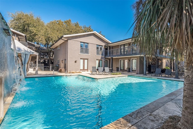 view of swimming pool with pool water feature and a patio area