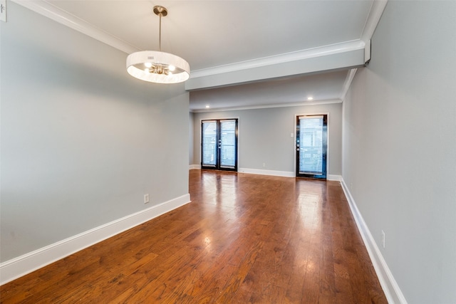 spare room featuring ornamental molding, dark hardwood / wood-style flooring, and a notable chandelier