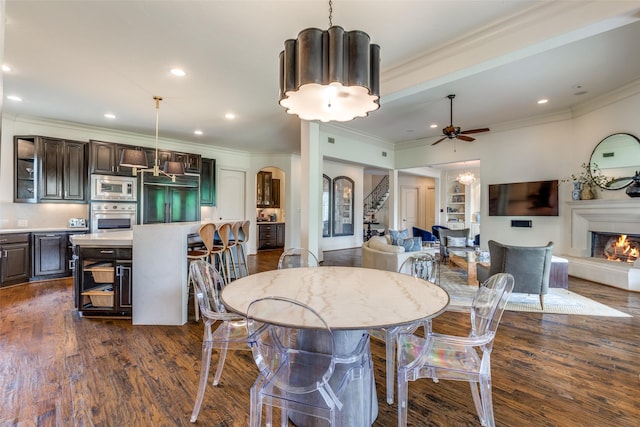 dining space featuring dark wood-type flooring, ceiling fan, and ornamental molding