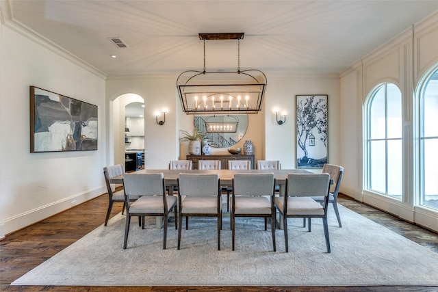 dining area featuring dark hardwood / wood-style flooring, ornamental molding, and a chandelier