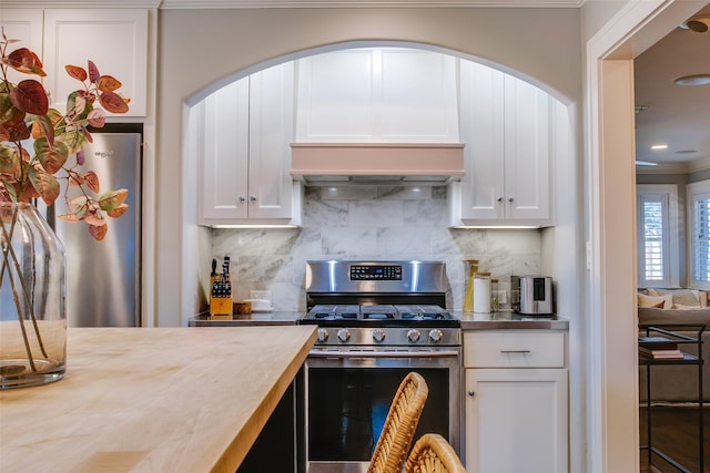 kitchen featuring white cabinetry, stainless steel range with gas cooktop, range hood, and tasteful backsplash