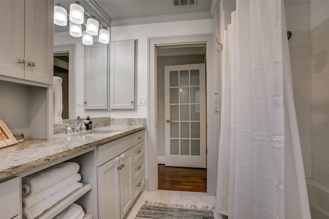 bathroom featuring ornamental molding, shower / bathtub combination with curtain, and vanity