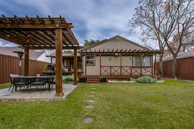 rear view of property with a pergola, a lawn, and a patio