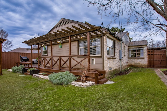 back of house featuring a pergola, a deck, and a lawn