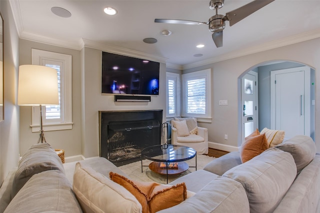 living room with crown molding, a wealth of natural light, ceiling fan, and light wood-type flooring