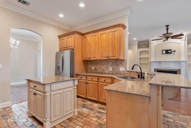 kitchen featuring crown molding, a kitchen island, sink, and stainless steel fridge with ice dispenser