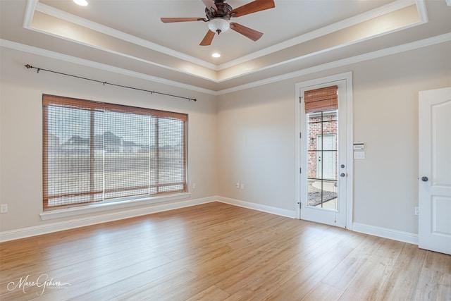 spare room with ornamental molding, plenty of natural light, a tray ceiling, and light hardwood / wood-style floors